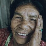 Close-up of a smiling elderly woman with a nose piercing showcasing her wrinkles and joyful expression.